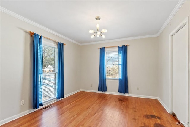 unfurnished room featuring visible vents, wood finished floors, a wealth of natural light, and an inviting chandelier