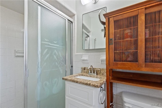 bathroom with toilet, a stall shower, vanity, and tile walls