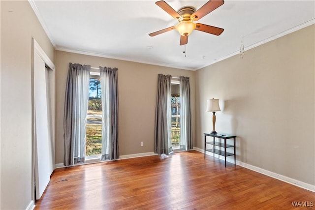 unfurnished room featuring ornamental molding, baseboards, and wood finished floors