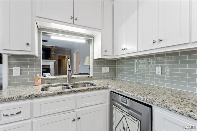 kitchen featuring wine cooler, white cabinetry, a sink, and decorative backsplash