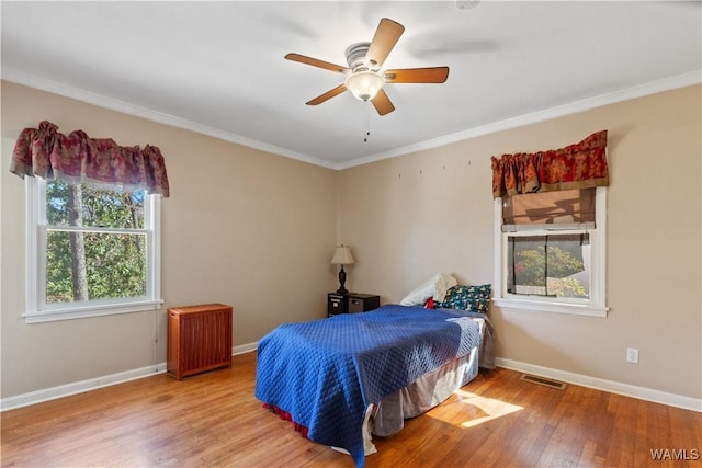 bedroom featuring light wood-style floors, baseboards, visible vents, and crown molding