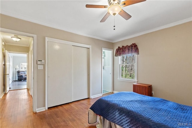 bedroom featuring light wood-style flooring, a ceiling fan, baseboards, ornamental molding, and radiator