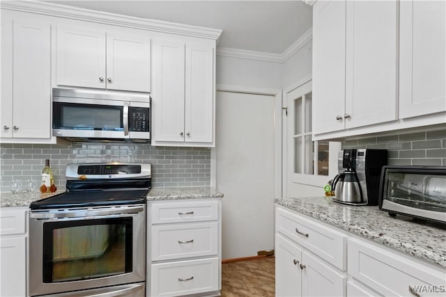 kitchen with stainless steel appliances, ornamental molding, white cabinetry, and decorative backsplash