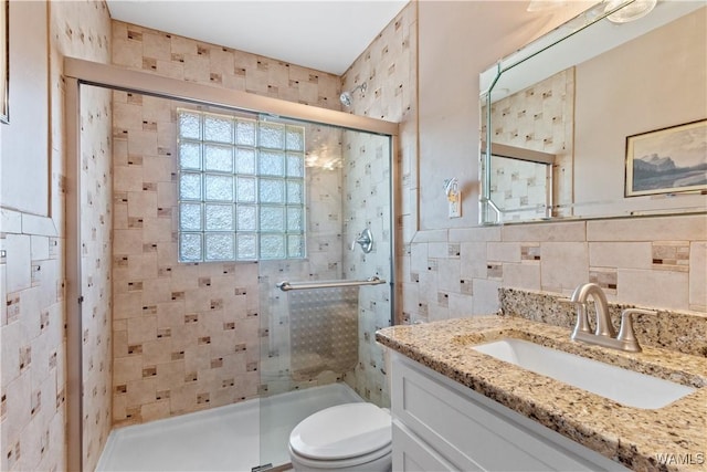 bathroom featuring toilet, vanity, a shower stall, and tile walls