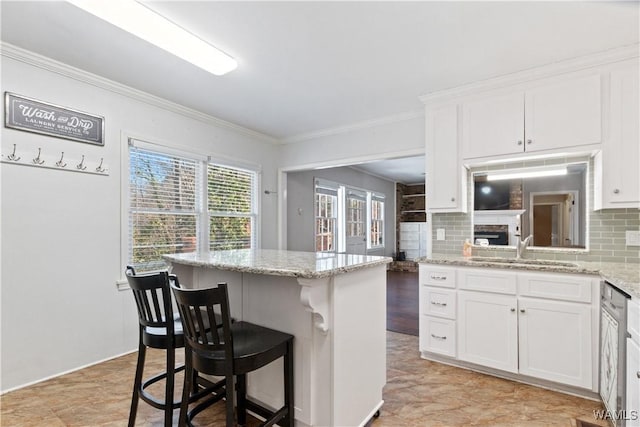 kitchen with a breakfast bar, decorative backsplash, a sink, and white cabinets