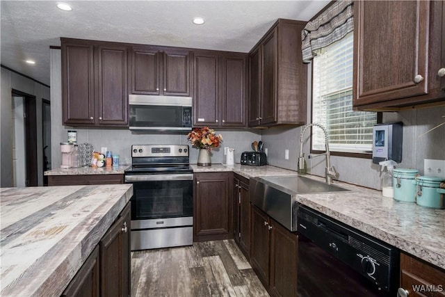 kitchen with butcher block countertops, sink, dark wood-type flooring, appliances with stainless steel finishes, and dark brown cabinets