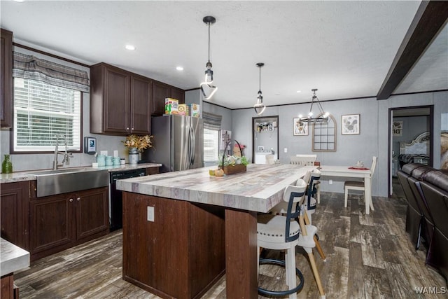 kitchen with a kitchen island, dishwasher, sink, stainless steel fridge, and hanging light fixtures