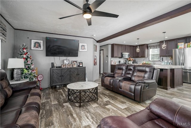 living room with beamed ceiling, ceiling fan, ornamental molding, and light hardwood / wood-style flooring