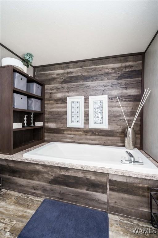 bathroom with a relaxing tiled tub and wooden walls