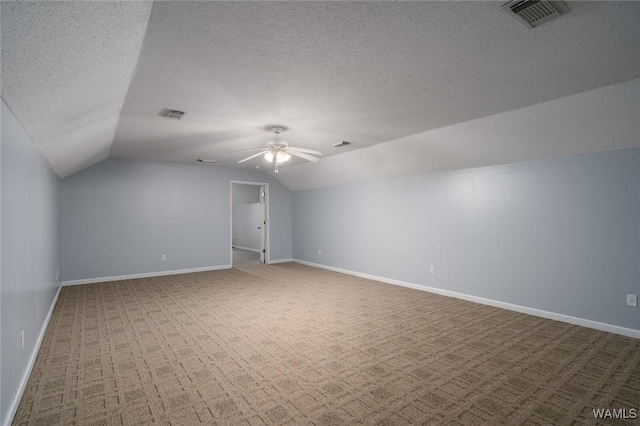 additional living space with ceiling fan, vaulted ceiling, a textured ceiling, and carpet flooring