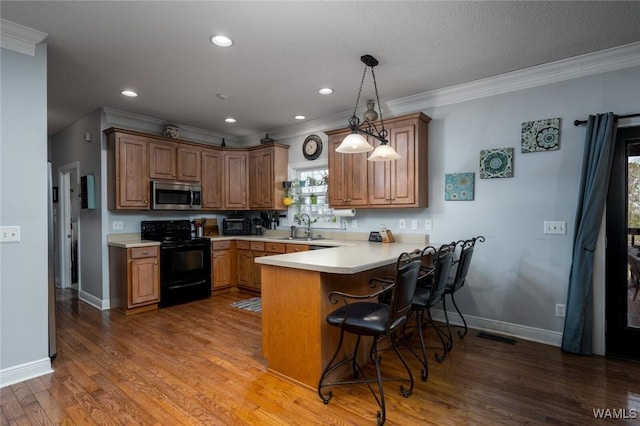 kitchen with a breakfast bar, sink, decorative light fixtures, black electric range, and kitchen peninsula