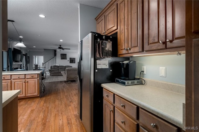 kitchen with stainless steel fridge, hanging light fixtures, ceiling fan, a textured ceiling, and light hardwood / wood-style flooring