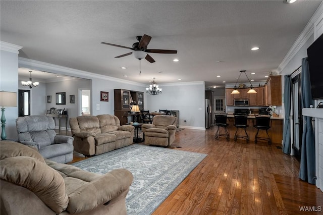 living room with hardwood / wood-style flooring, ornamental molding, ceiling fan with notable chandelier, and a textured ceiling