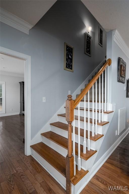 stairs with hardwood / wood-style flooring and ornamental molding