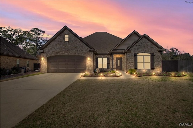 view of front of home featuring concrete driveway, an attached garage, fence, a front lawn, and brick siding