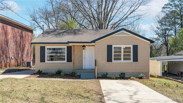 bungalow-style home featuring central AC, a shingled roof, a front yard, and concrete block siding