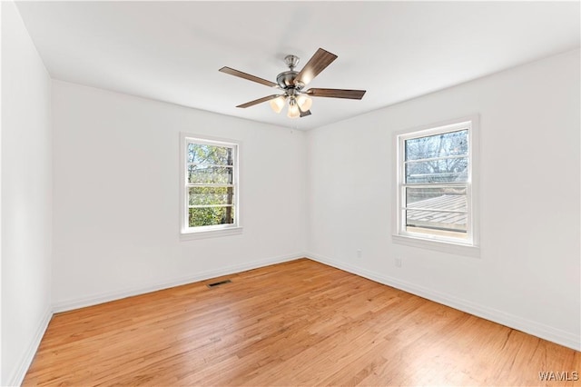 spare room featuring light wood-style floors, baseboards, visible vents, and a ceiling fan