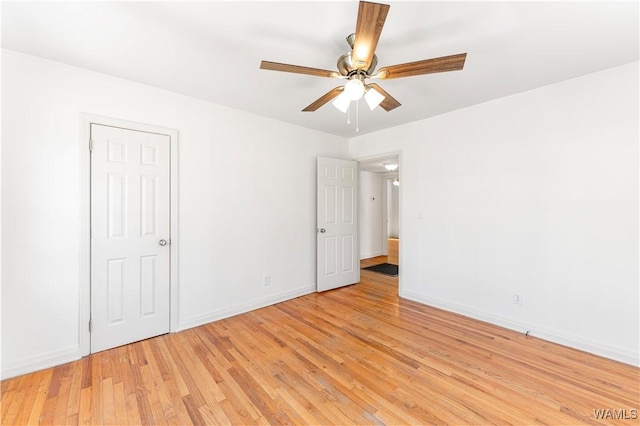 empty room featuring a ceiling fan, baseboards, and light wood finished floors