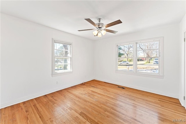 empty room with a ceiling fan, light wood-type flooring, visible vents, and baseboards