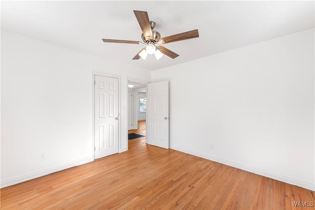 spare room featuring light wood-type flooring, a ceiling fan, and baseboards