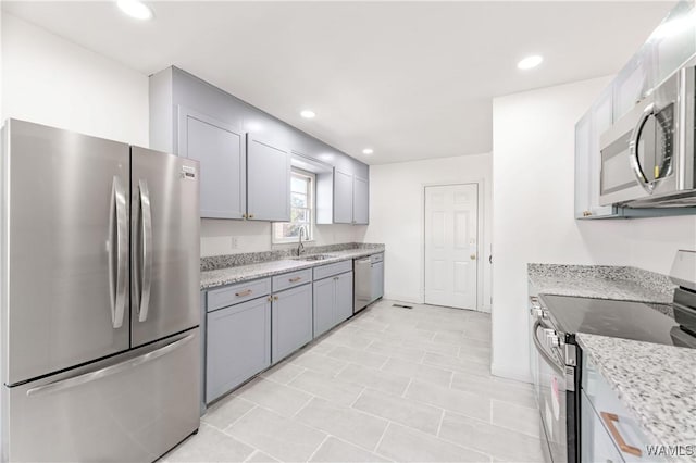 kitchen with stainless steel appliances, recessed lighting, gray cabinetry, and light stone countertops