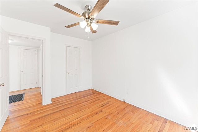 unfurnished bedroom with a ceiling fan, light wood-style flooring, visible vents, and baseboards