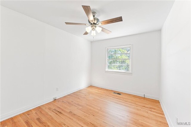 spare room with ceiling fan, light wood finished floors, visible vents, and baseboards