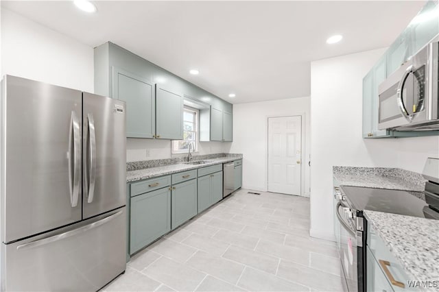 kitchen with light stone countertops, appliances with stainless steel finishes, a sink, and recessed lighting