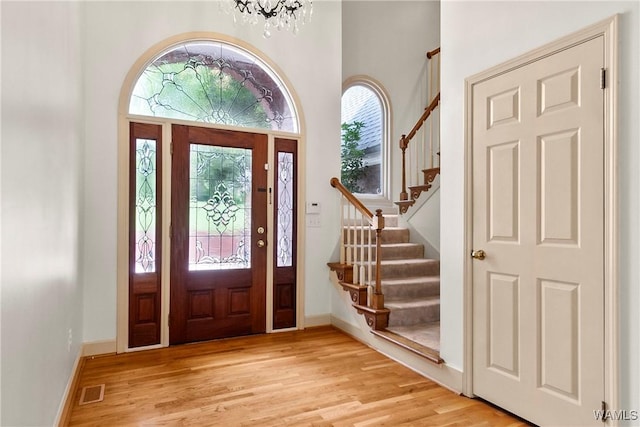 6803 Emerald Ln, Tuscaloosa, AL 35406 - entrance foyer with light wood finished floors, a chandelier, stairs, baseboards, and a towering ceiling