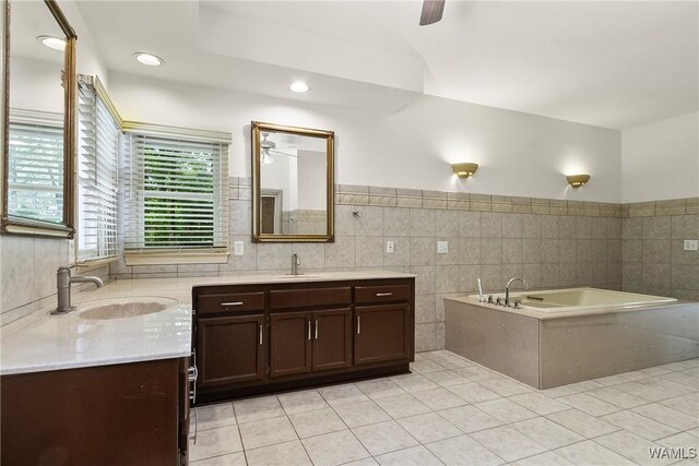 6803 Emerald Ln, Tuscaloosa, AL 35406 - bathroom featuring a ceiling fan, two vanities, tile patterned floors, a bath, and tile walls