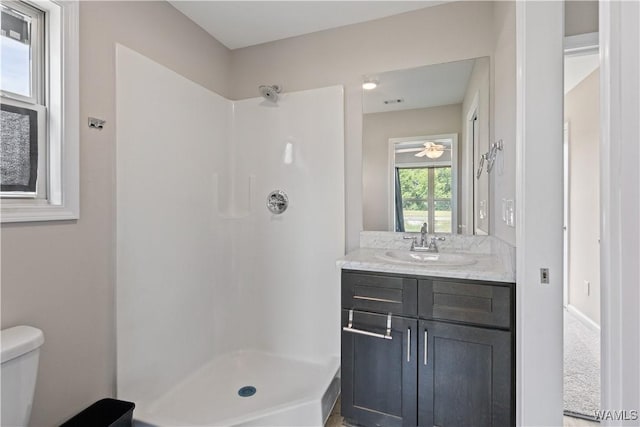 bathroom featuring walk in shower, vanity, ceiling fan, and toilet