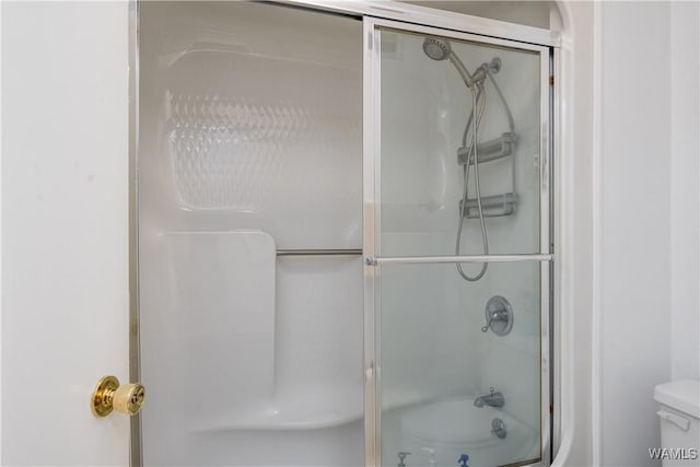 bathroom featuring enclosed tub / shower combo and toilet