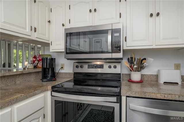 kitchen with appliances with stainless steel finishes, white cabinets, and tile counters