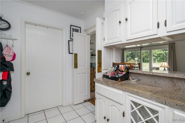 kitchen with light tile patterned floors, white cabinetry, and crown molding