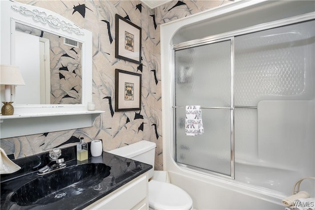 full bath with bath / shower combo with glass door, vanity, toilet, and wallpapered walls