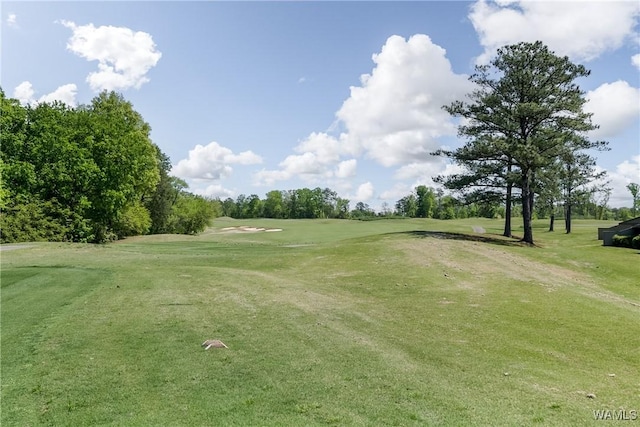 view of property's community with view of golf course and a yard