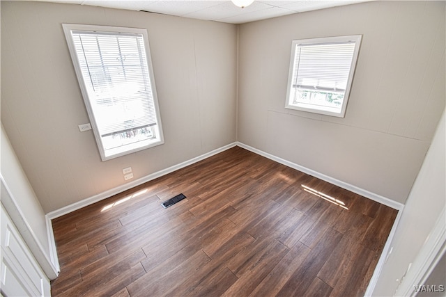 spare room featuring a paneled ceiling and dark hardwood / wood-style flooring