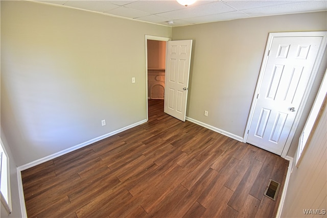 unfurnished bedroom with a paneled ceiling and dark wood-type flooring