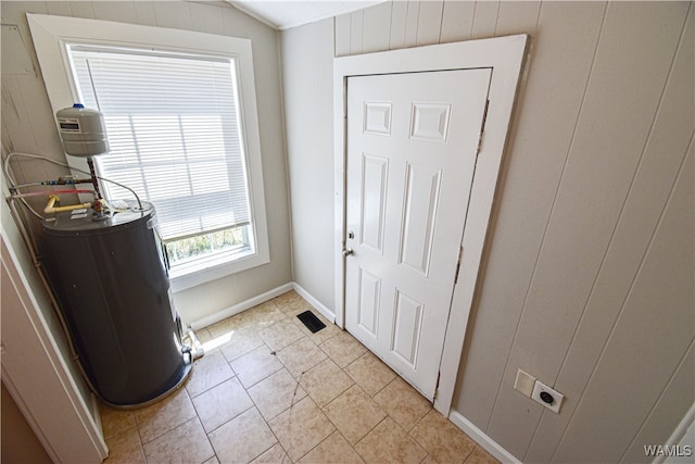 tiled entrance foyer featuring wooden walls and water heater