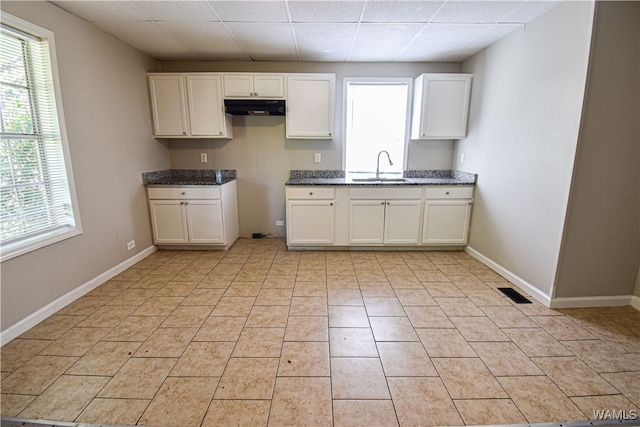 kitchen with a paneled ceiling, white cabinetry, sink, and light tile patterned floors