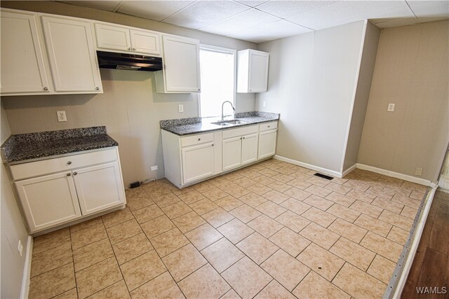 kitchen featuring white cabinets, dark stone countertops, and sink