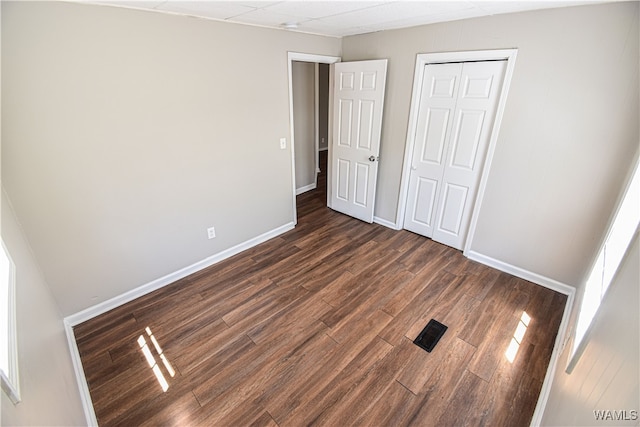 unfurnished bedroom with a closet and dark wood-type flooring