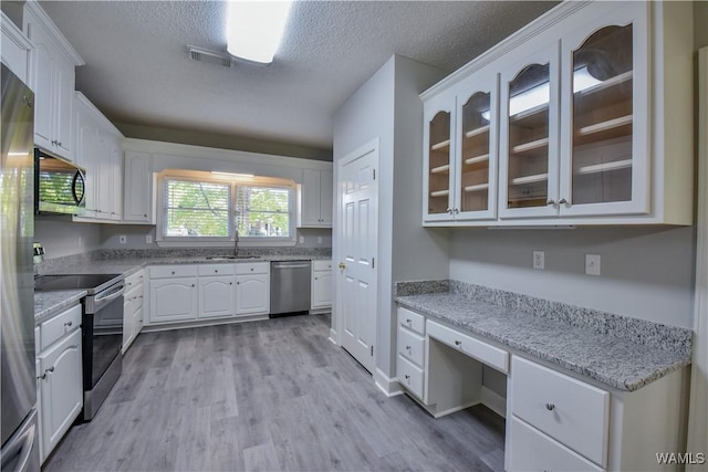 kitchen with light stone countertops, white cabinetry, sink, stainless steel appliances, and a textured ceiling