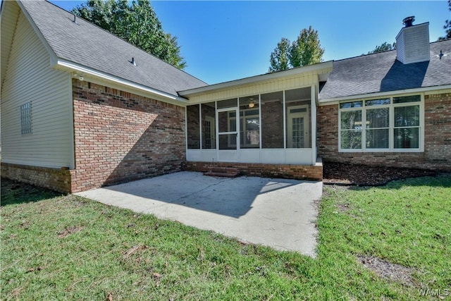 rear view of house featuring a yard, a patio, and a sunroom