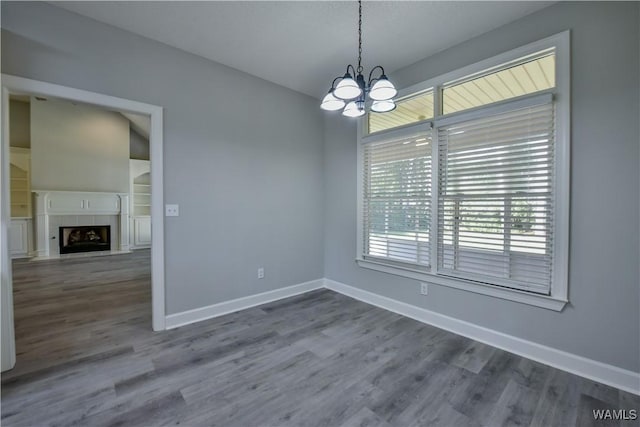 interior space featuring a tile fireplace, a chandelier, and hardwood / wood-style flooring