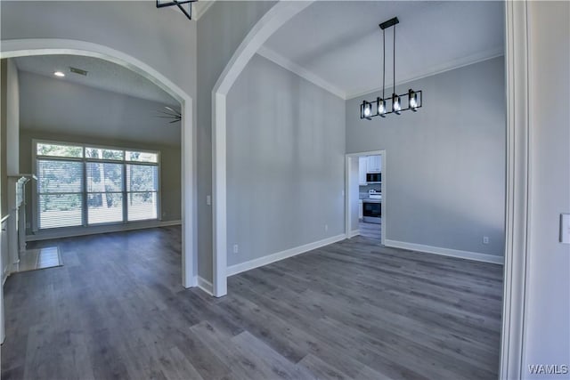 unfurnished dining area with a high ceiling, dark hardwood / wood-style flooring, ceiling fan, and crown molding