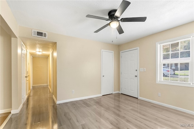 unfurnished room featuring ceiling fan, light wood-type flooring, and a textured ceiling