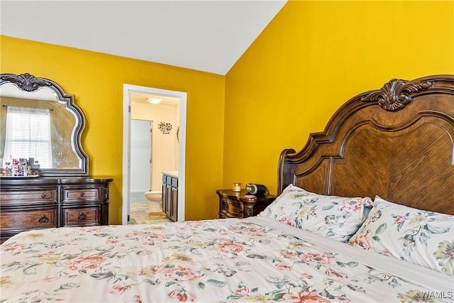 bedroom featuring ensuite bath and vaulted ceiling