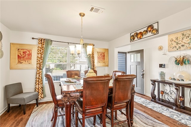 dining room with wood-type flooring and a notable chandelier