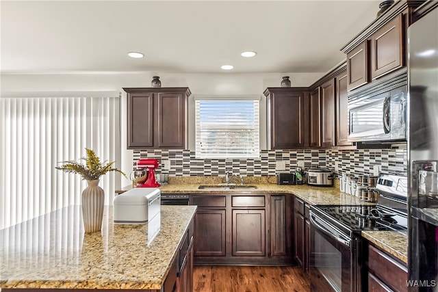 kitchen with hardwood / wood-style floors, sink, light stone countertops, tasteful backsplash, and stainless steel appliances